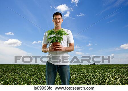 Man holding plant in field View Large Photo Image Picture - Man holding plant in field. Fotosearch