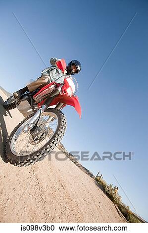 Stock Image - Man riding dirt bike on dirt track. Fotosearch