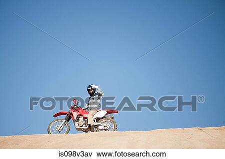 Stock Photo - Man riding dirt bike on hill. Fotosearch