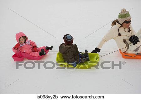 Stock Image - Mother pulling two children on sledges. Fotosearch