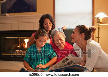 Stock Photograph - Three generation family looking at photo album. Fotosearch