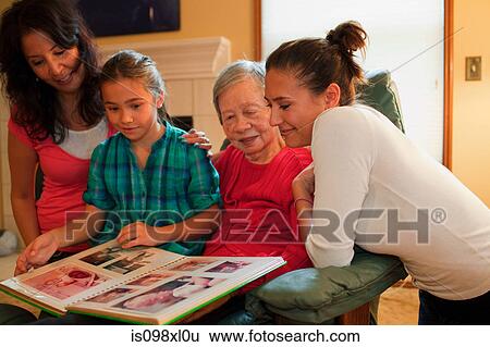 Three generation family looking at photo album View Large Photo Image Stock Photograph - Three generation family looking at photo album. Fotosearch