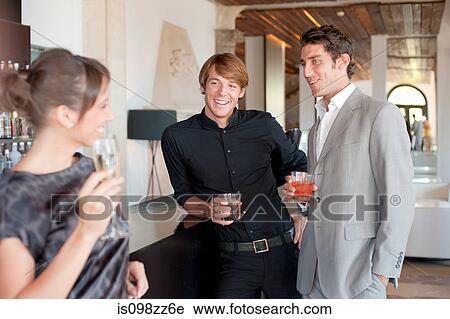 Stock Image - Two men flirting with woman in bar. Fotosearch