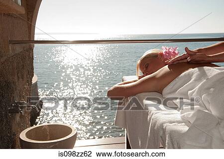 Stock Image - Woman having massage by the ocean. Fotosearch
