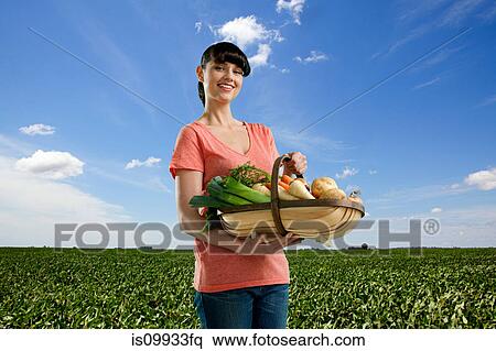 Woman in field holding basket of homegrown vegetables View Large Photo Image Stock Photography - Woman in field holding basket of homegrown vegetables. Fotosearch