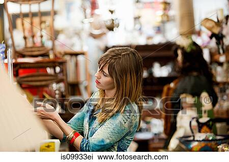 Woman inspecting items for sale in antiques shop View Large Photo Image Stock Image - Woman inspecting items for sale in antiques shop. Fotosearch