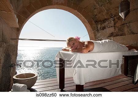 Woman lying on massage table by the ocean View Large Photo Image Stock Image - Woman lying on massage table by the ocean. Fotosearch