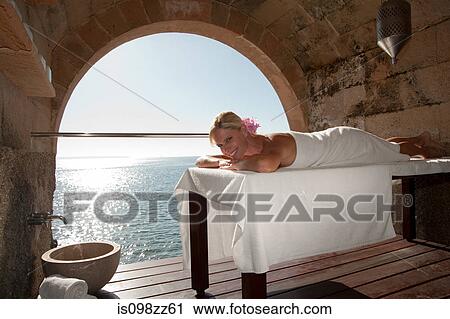 Woman lying on massage table by the ocean View Large Photo Image Stock Image - Woman lying on massage table by the ocean. Fotosearch