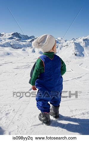 Stock Photography - Young boy standing looking at mountains in snow. Fotosearch