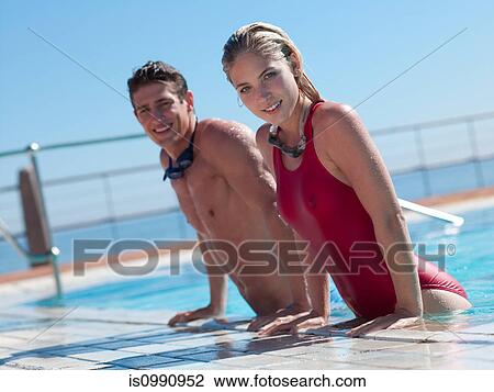 Stock Image - Young couple exiting swimming pool. Fotosearch
