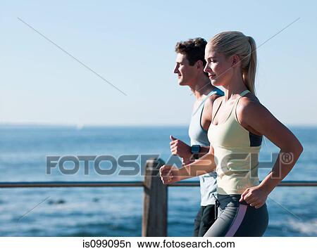 Young couple running by sea View Large Photo Image Picture - Young couple running by sea. Fotosearch