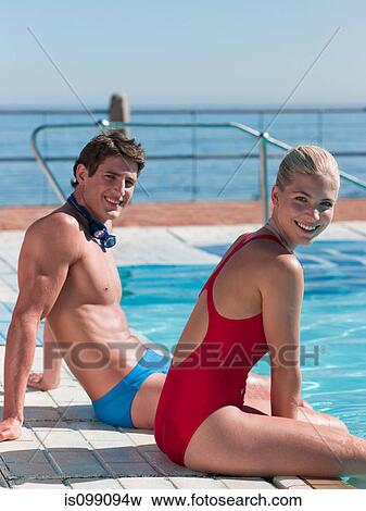 Stock Photo - Young couple sitting at poolside, portrait. Fotosearch