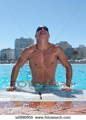 Stock Photography - Young man exiting swimming pool. Fotosearch