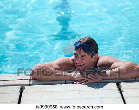 Stock Photo - Young man resting on poolside, portrait. Fotosearch