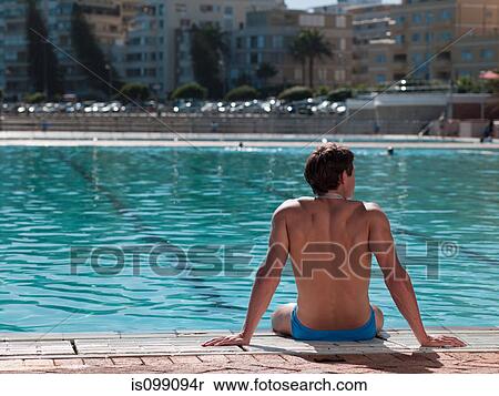 Young man sitting at poolside View Large Photo Image Stock Photography - Young man sitting at poolside. Fotosearch