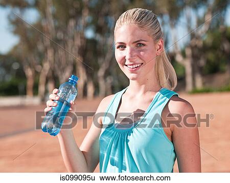 Stock Photograph - Young woman holding bottle of mineral water. Fotosearch