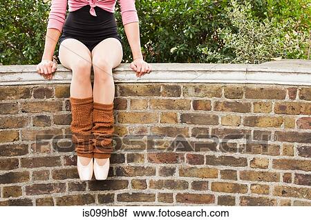 Stock Image - Ballerina sitting on wall, low section. Fotosearch