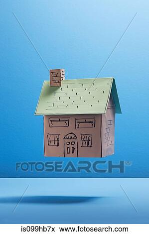 Stock Photo - Floating cardboard house against blue background. Fotosearch