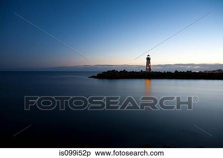 Lighthouse overlooking calm water at dusk View Large Photo Image Stock Photography - Lighthouse overlooking calm water at dusk. Fotosearch