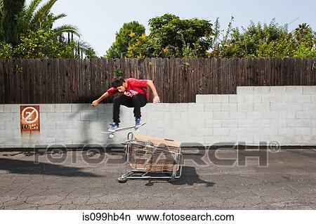 Man on skateboard jumping over a shopping trolley View Large Photo Image Picture - Man on skateboard jumping over a shopping trolley. Fotosearch