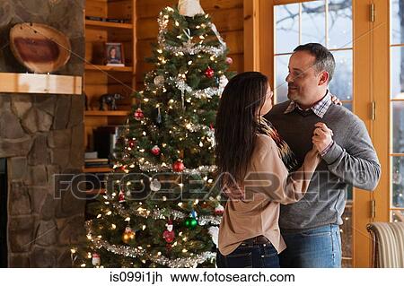 Stock Image - Mature couple dancing by Christmas tree. Fotosearch