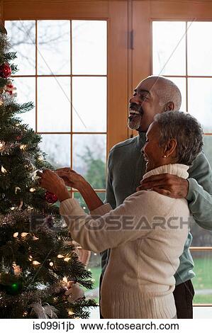 Stock Image - Mature couple decorating Christmas tree. Fotosearch