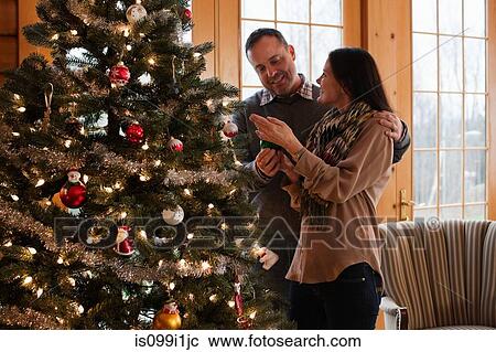 Stock Image - Mature couple decorating Christmas tree. Fotosearch