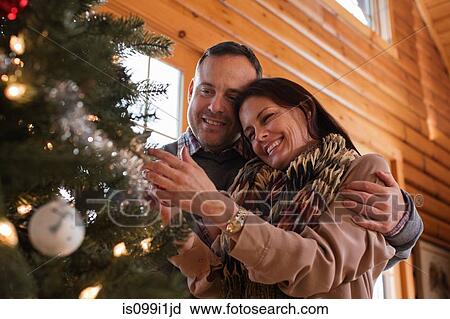 Stock Image - Mature couple decorating Christmas tree. Fotosearch