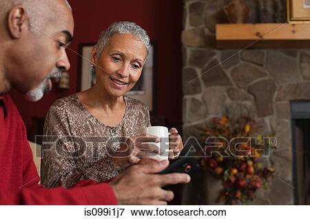 Mature couple looking at cellphone by fireplace View Large Photo Image Stock Photo - Mature couple looking at cellphone by fireplace. Fotosearch