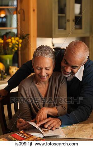 Mature couple looking through book together View Large Photo Image Stock Image - Mature couple looking through book together. Fotosearch