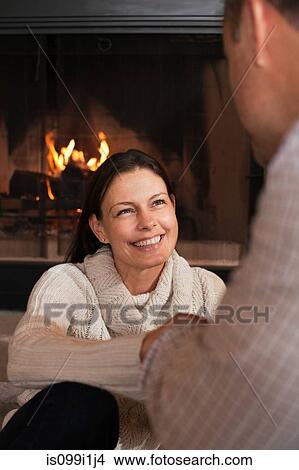 Mature couple relaxing by fireplace, smiling View Large Photo Image Picture - Mature couple relaxing by fireplace, smiling. Fotosearch