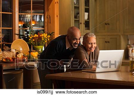 Mature couple using laptop in kitchen View Large Photo Image Stock Image - Mature couple using laptop in kitchen. Fotosearch