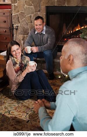 Mature friends relaxing by fireplace View Large Photo Image Stock Image - Mature friends relaxing by fireplace. Fotosearch