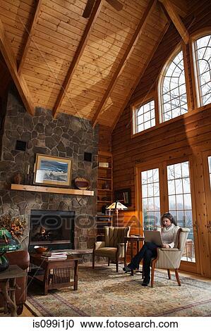 Stock Image - Mature woman relaxing in armchair of living room. Fotosearch