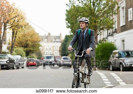 Stock Photo - Mid adult businessman riding bicycle on street. Fotosearch