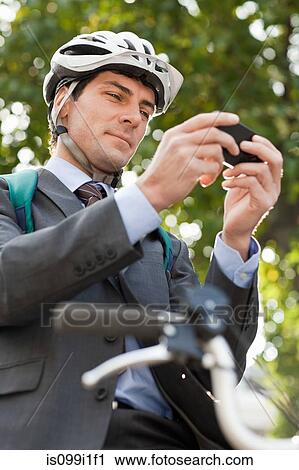 Mid adult businessman using cellphone to text on bicycle View Large Photo Image Stock Image - Mid adult businessman using cellphone to text on bicycle. Fotosearch