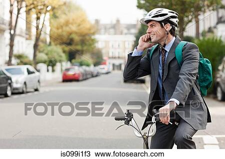 Mid adult businessman using cellphone on bicycle View Large Photo Image Stock Image - Mid adult businessman using cellphone on bicycle. Fotosearch