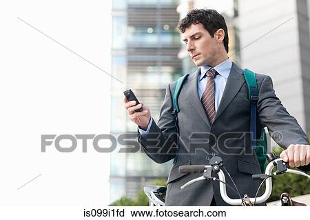 Mid adult businessman with bike using cellphone View Large Photo Image Stock Image - Mid adult businessman with bike using cellphone. Fotosearch