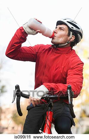 Mid adult man drinking on bicycle View Large Photo Image Stock Image - Mid adult man drinking on bicycle. Fotosearch