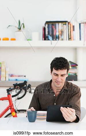 Mid adult man using digital tablet at home View Large Photo Image Stock Photography - Mid adult man using digital tablet at home. Fotosearch