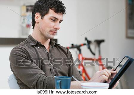 Mid adult man using digital tablet at home View Large Photo Image Stock Photography - Mid adult man using digital tablet at home. Fotosearch