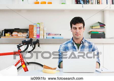 Mid adult man using laptop at home View Large Photo Image Picture - Mid adult man using laptop at home. Fotosearch