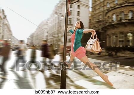 Mid adult woman in pink dress leaping through city streets View Large Photo Image Stock Photo - Mid adult woman in pink dress leaping through city streets. Fotosearch
