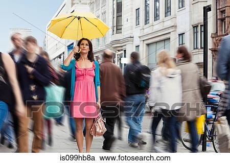 Mid adult woman in pink dress standing still with umbrella in crowded city View Large Photo Image Stock Image - Mid adult woman in pink dress standing still with umbrella in crowded city. Fotosearch