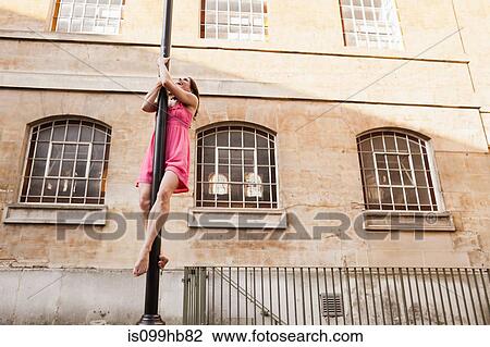 Mid adult woman in pink dress performing dance on street lamp in city View Large Photo Image Stock Image - Mid adult woman in pink dress performing dance on street lamp in city. Fotosearch