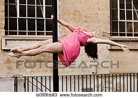 Mid adult woman in pink dress performing dance on street lamp in city View Large Photo Image Stock Image - Mid adult woman in pink dress performing dance on street lamp in city. Fotosearch