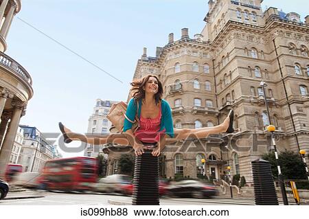Stock Photo - Mid adult woman in pink dress leapfrogging through city street. Fotosearch