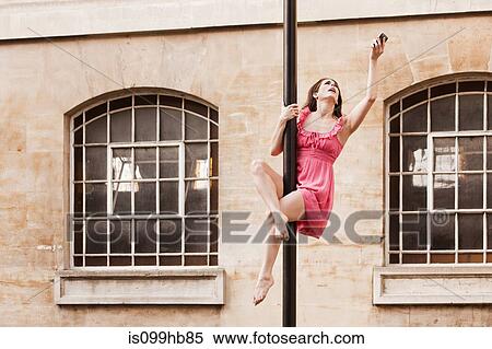 Mid adult woman in pink dress using cellphone on street lamp in city View Large Photo Image Stock Photography - Mid adult woman in pink dress using cellphone on street lamp in city. Fotosearch