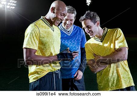 Soccer players looking at cellphone on pitch View Large Photo Image Picture - Soccer players looking at cellphone on pitch. Fotosearch