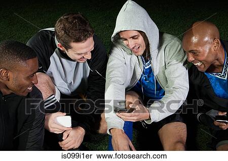 Soccer players looking at cellphone on pitch View Large Photo Image Stock Photography - Soccer players looking at cellphone on pitch. Fotosearch